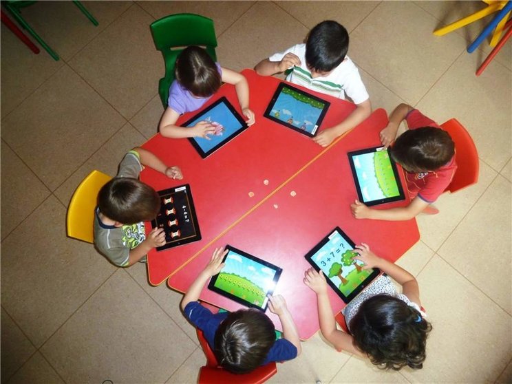 Niños usando tabletas en el colegio (imagen de archivo)